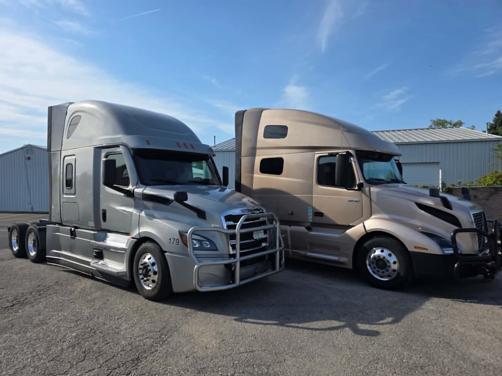 Freightliner Cascadia and Volvo VNL sleeper tractors parked at the terminal